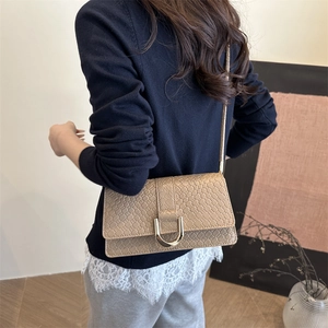 Light brown woven texture crossbody bag with gold D-buckle and slim shoulder strap