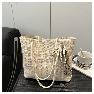 Close-up of beige woven tote bag with herringbone texture and decorative silk scarf