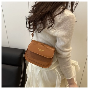 Detail of a brown saddle bag with gold FASHION & BAGS lettering and adjustable strap