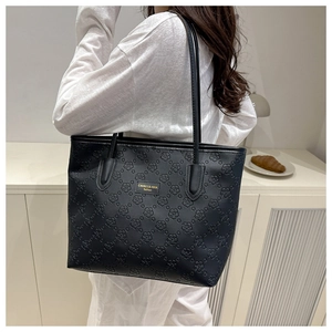 Détail d'un cabas en cuir noir avec gaufrage floral 3D et plaque logo dorée