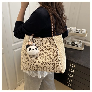 Detail einer Canvas-Tragetasche mit Cartoon-Panda-Print und Plüsch-Panda-Anhänger