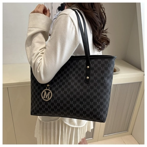 Detail shot of the M-letter print pattern and metal charm on a large tote bag