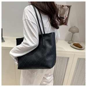 Detailed view of black tote bag featuring embossed floral patterns on premium synthetic leather