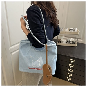 Light blue canvas tote bag with embroidered cartoon dog and brown leather accessory charm
