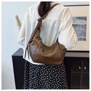 Detail of vintage coffee leather hobo bag with knotted shoulder strap on a model