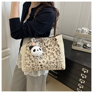 Detail der Strohtasche mit braunen Griffen und Panda-Plüsch-Anhänger in der Seitenansicht