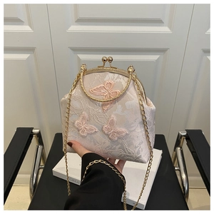 Détail du sac coquille en dentelle florale avec papillons 3D et fermoir doré vintage