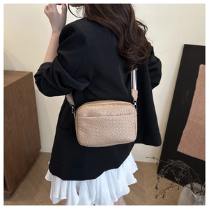 Detail of woven texture beige crossbody bag with adjustable striped fabric strap