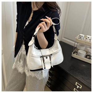 Detail of white vintage crescent bag with metal buckles and Y2K zip pockets