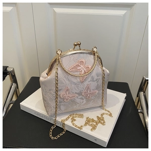 Détail du sac vintage en dentelle brodée de papillons avec poignée ronde dorée