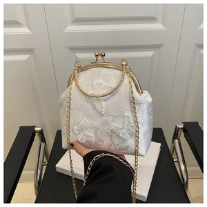 Détail du sac coquillage en dentelle blanche avec broderie papillon 3D et poignée dorée