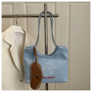 Detail of light blue denim tote bag with white puppy embroidery and winter stories text