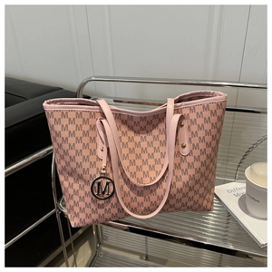 Detail of a large pink tote bag with brown M patterns and a stylish metal M charm