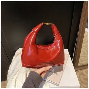 Détail du sac en cuir verni rouge vif avec boucle dorée et finition brillante