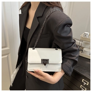 Detail of white PU leather crossbody bag with geometric buckle on a model in black suit