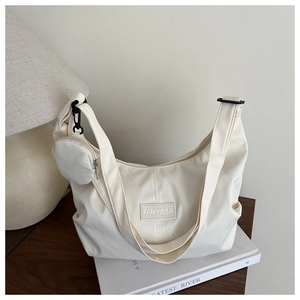 Dettaglio della borsa a mezzaluna crema con texture in nylon e piccolo borsellino