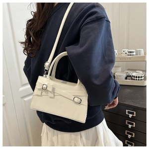 Gros plan du sac à bandoulière blanc avec nœud et sangle ajustable sur un mannequin