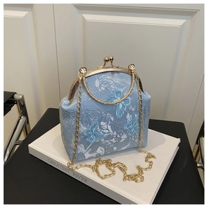 Détail du sac coquillage bleu clair avec papillons 3D et poignée en métal doré