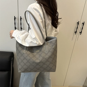 Sac cabas gris à motif floral avec plaque dorée porté par un mannequin pour le travail