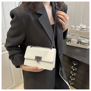 Close-up of white glossy patent leather shoulder bag with dark metal chain strap and clasp