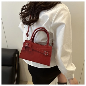 Détail du sac bandoulière rouge avec boucle noeud porté par un mannequin en studio