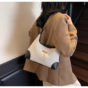 Close-up of a stylish canvas tote bag with black leather accents and gold deer charm