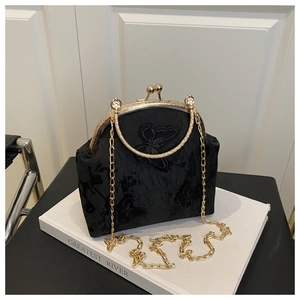 Détail d'un sac vintage brodé de papillons et de fleurs avec une poignée en métal doré chic