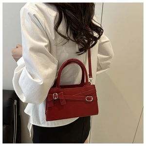 Détail du petit sac bandoulière rouge avec lanières en cuir et boucles métalliques