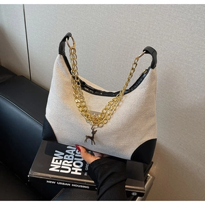 Close-up of contrast tote with woven fabric, black leather trim and deer pendant