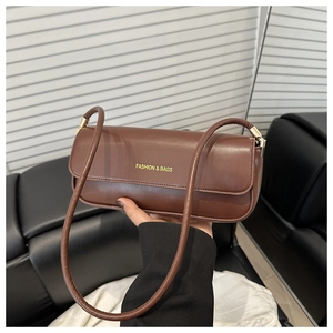 Close-up of a dark brown baguette bag with gold lettering and smooth leather texture