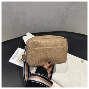 Close-up of khaki woven camera bag with trendy contrast striped wide shoulder strap