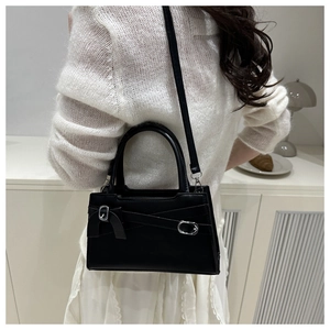 Sac bandoulière noir chic avec boucle en métal et nœud porté par un mannequin