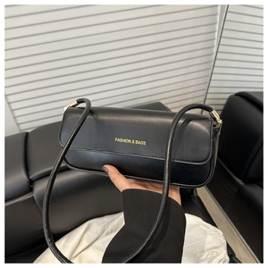 Close-up of black baguette bag featuring gold logo and textured leather surface