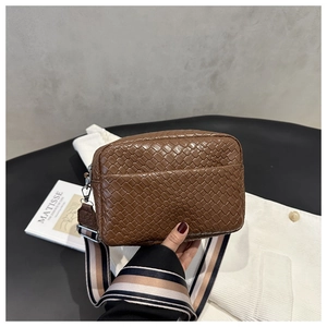 Detailed close-up of brown woven leather texture and striped wide shoulder strap
