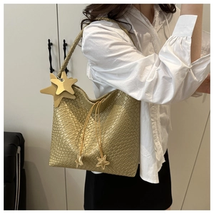 Detail of gold woven tote bag featuring metallic texture and star pendant charms