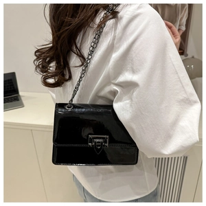 Détail du sac bandoulière en cuir verni noir avec une chaîne en métal gris élégante