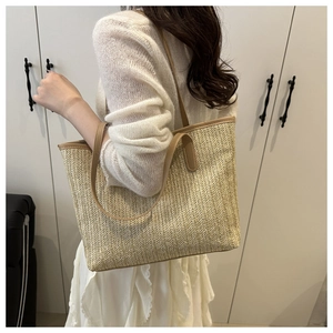 Detail of light beige straw tote bag with brown handles and V-shaped woven pattern