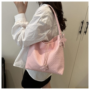 Detail of pink woven tote bag with star charm and drawstring, shown on shoulder