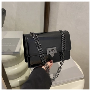 Détail du sac à rabat en cuir verni noir brillant avec chaîne grise et fermoir géométrique
