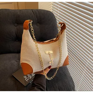 Detail of beige fabric shoulder bag with brown leather trim and gold deer charm