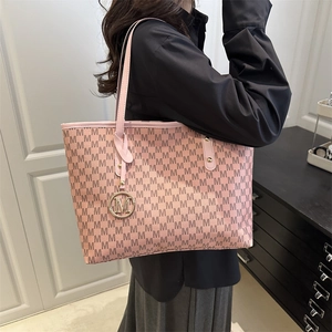 Pink tote bag with letter M print and gold charm shown from a side-view angle