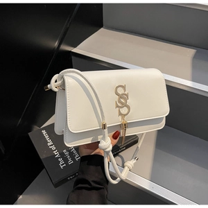 Detail of white leather crossbody bag with golden S-lock tassel and rope knot shoulder strap