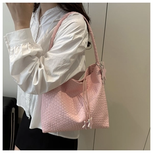 Detail of light pink woven tote bag featuring star pendants and shoulder strap style