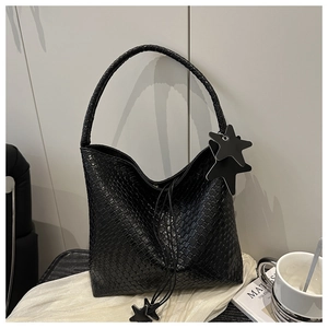 Close-up of black woven leather texture and star pendant on a minimalist tote bag