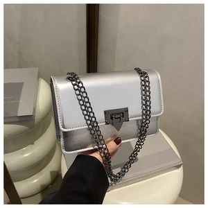 Détail d'un sac bandoulière argenté avec fermoir rotatif gris métal et bandoulière chaîne