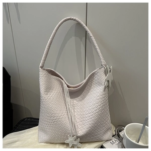 Detail of cream woven tote bag featuring soft mesh texture and star tassel charm