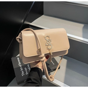 Detailed close-up of beige leather crossbody bag with gold interlocking logo and tassel charm