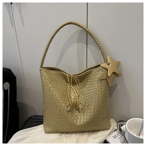Detail of gold woven tote bag featuring star charms and drawstring closure