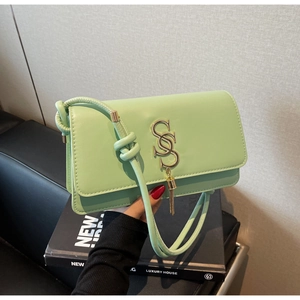 Detail of mint green leather crossbody bag with gold logo and tassel accent