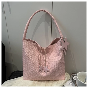 Detail of light pink woven tote bag featuring star charms and thick braided shoulder strap